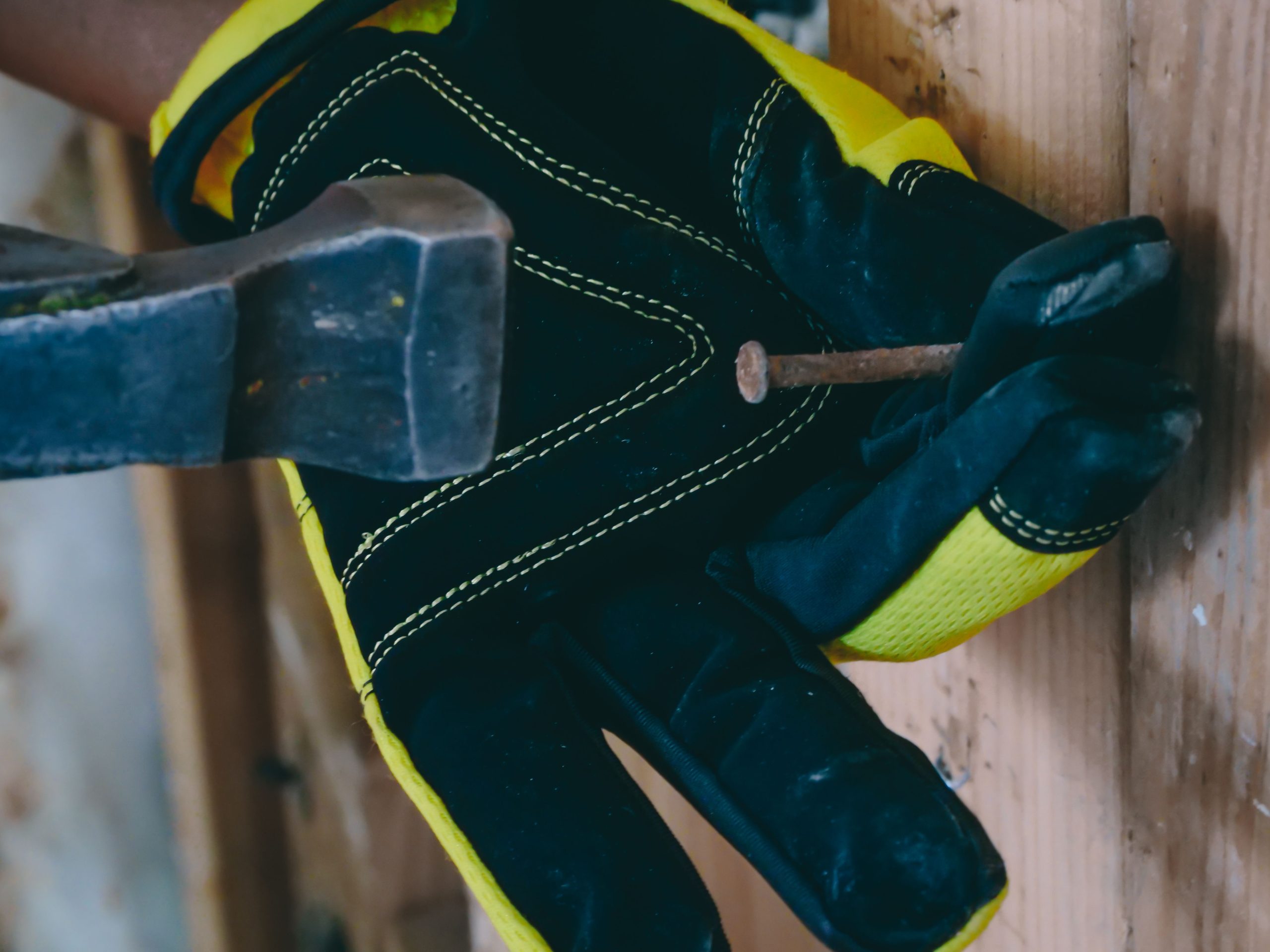 Ouvrier enfonçant un clou avec marteau et gants