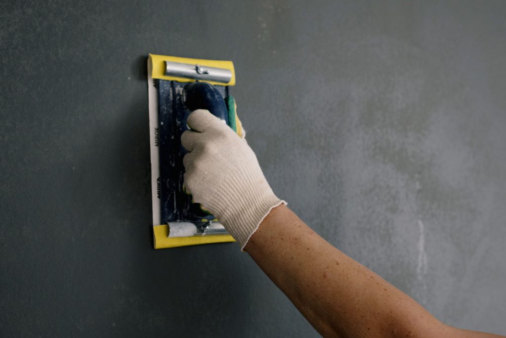 Homme en gants blanc rénovant murs avec couteau à mastic