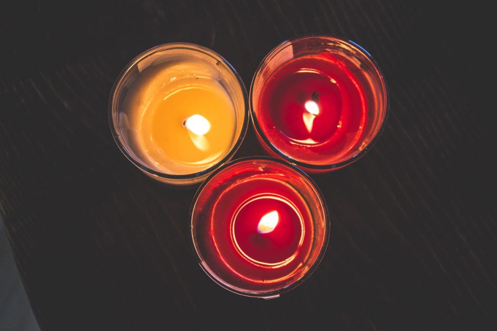 Trois bougies colorées allumées créant une ambiance chaleureuse
