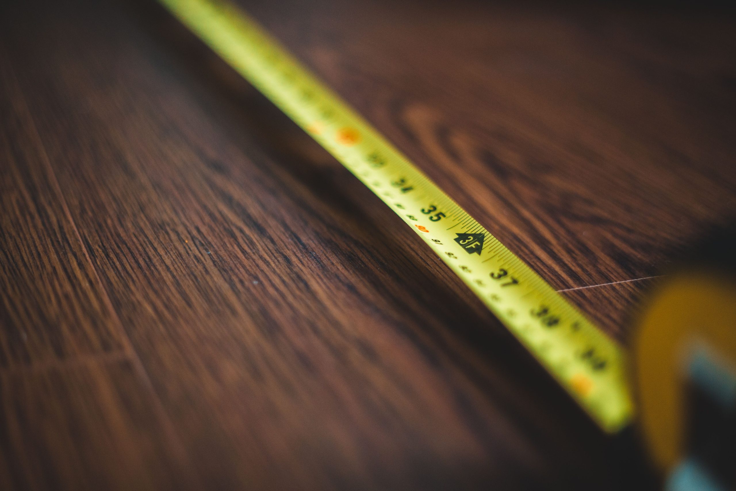 Mètre ruban jaune déroulé sur parquet bois