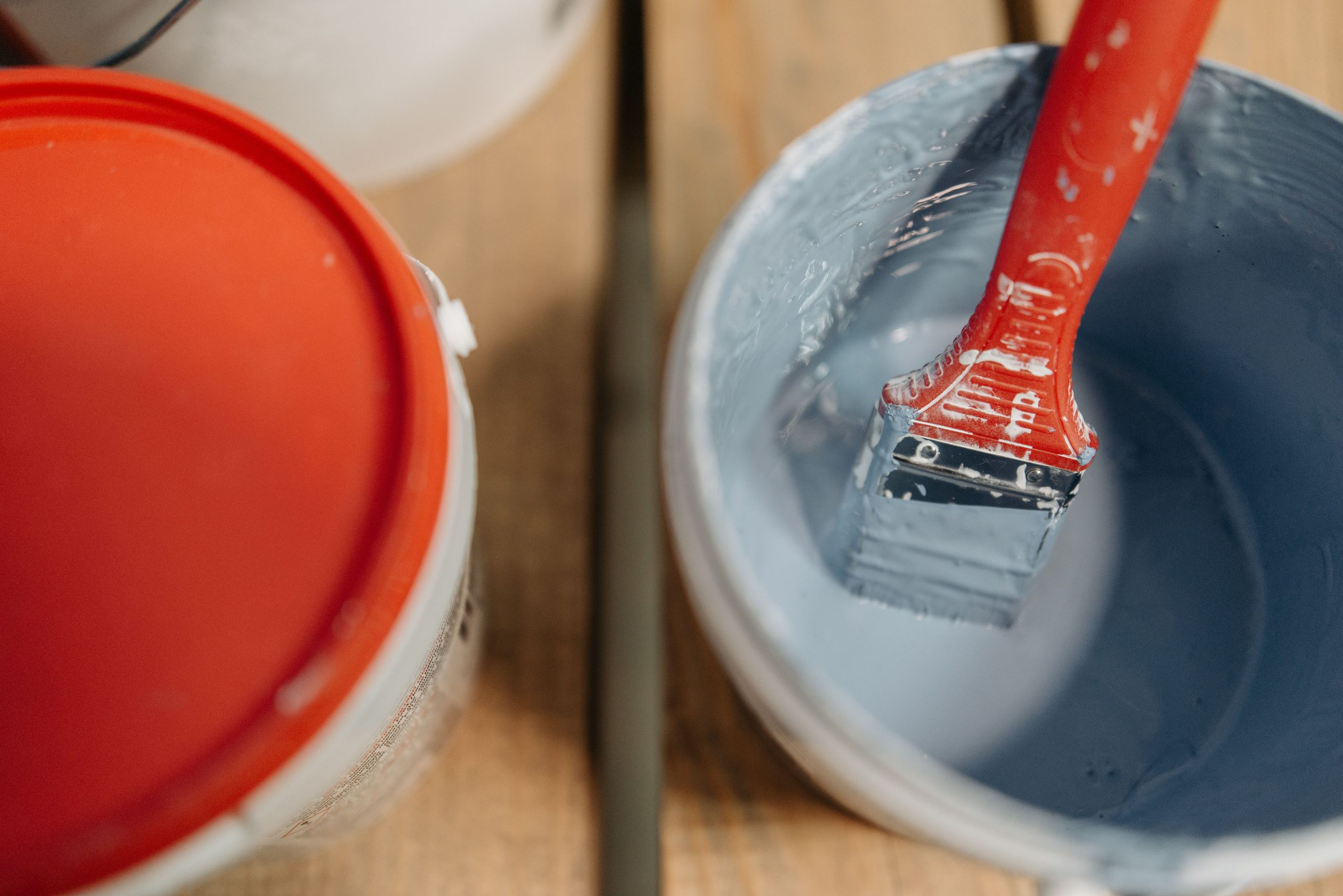 Pinceau bleu trempé dans seau peinture