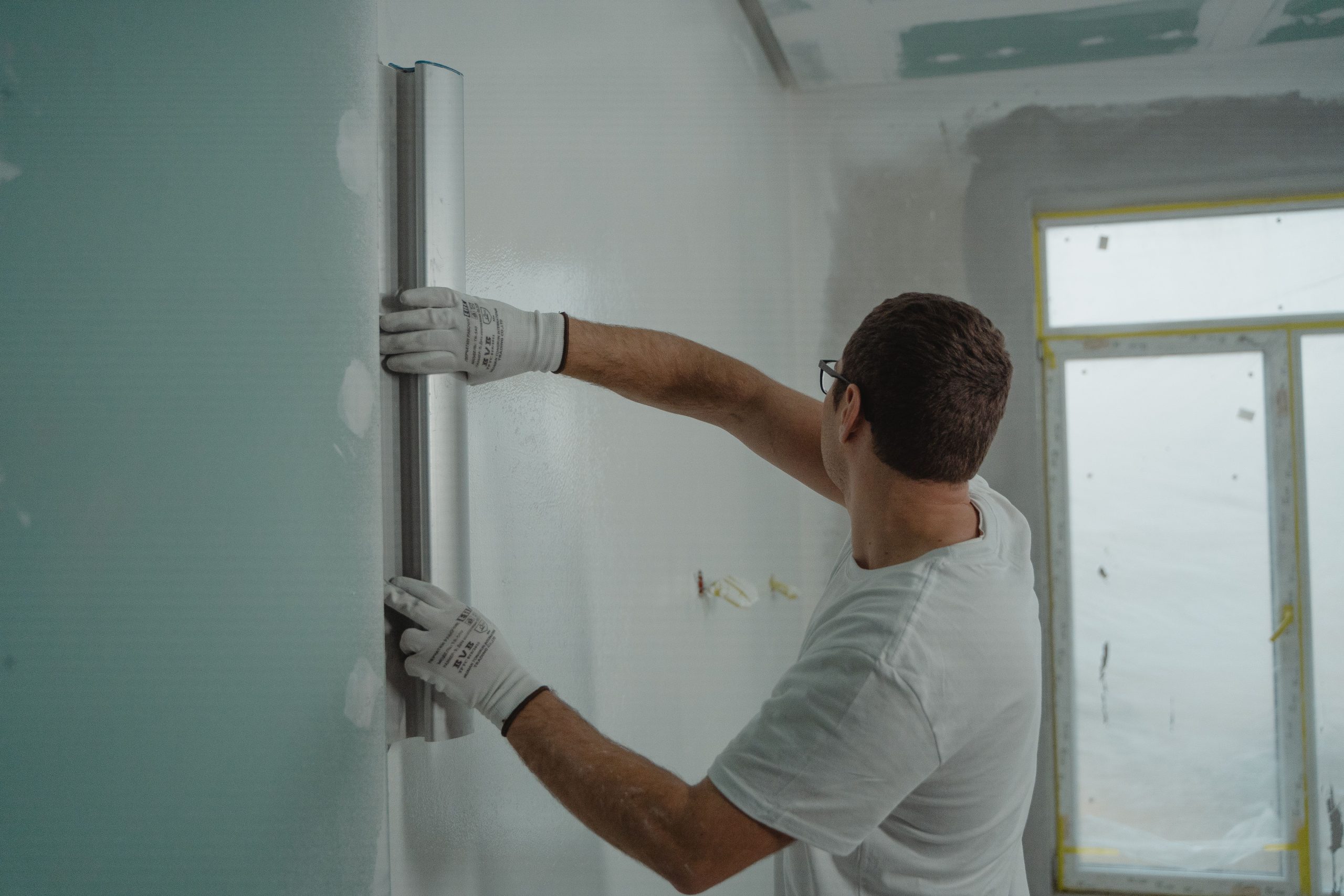 Homme utilisant règle métallique rénovation murale