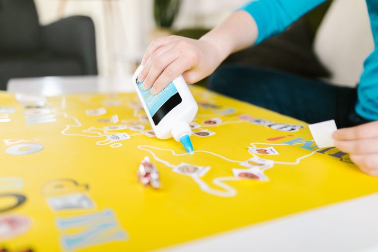 Mains appliquant colle PVA sur papier jaune