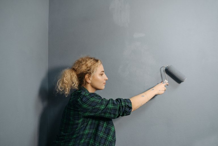 Femme appliquant peinture grise au rouleau