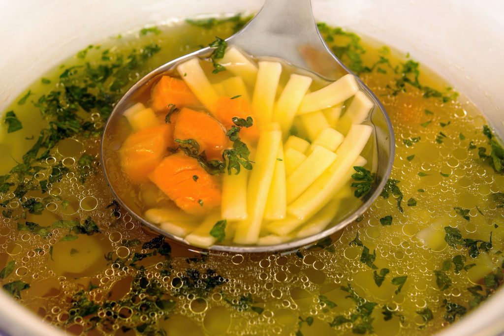 Louche de bouillon de poulet avec carottes et herbes
