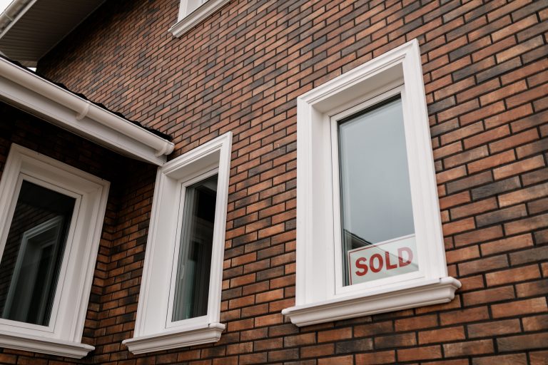 Maison en brique avec pancarte vendu