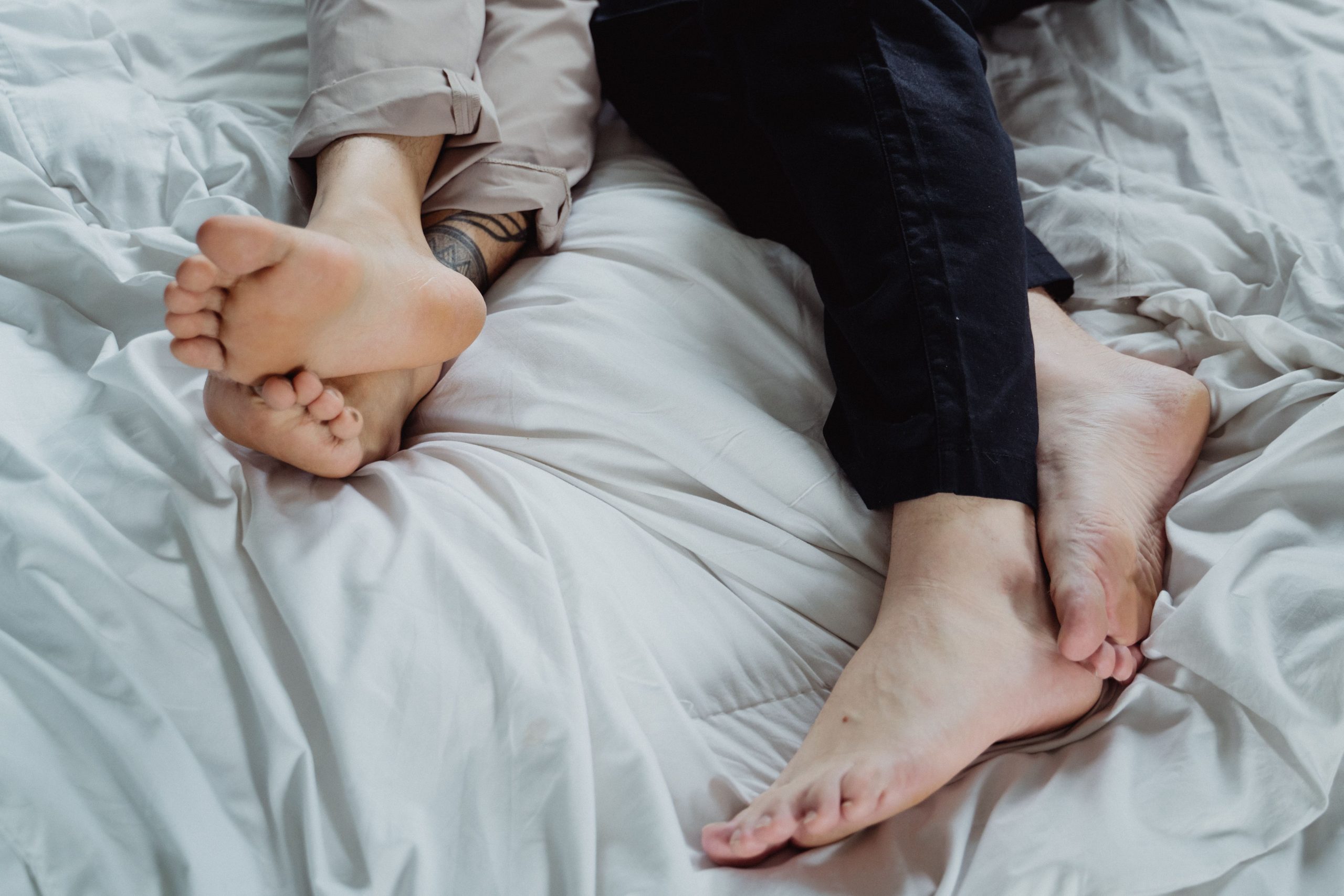 Pieds entrelacés sur un lit confortable